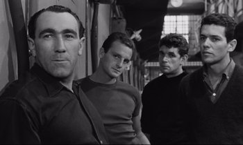 Movie still from “The Hole” (1960), directed by Jacques Becker – A black and white photo of a group of men standing together; Medium shot, Low angle