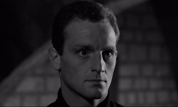 Movie still from “The Hole” (1960), directed by Jacques Becker – Black and white photograph of a man with a serious look; Close Up shot, Low angle