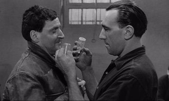 Movie still from “The Hole” (1960), directed by Jacques Becker – A couple of men are drinking something together; Close Up shot, High angle