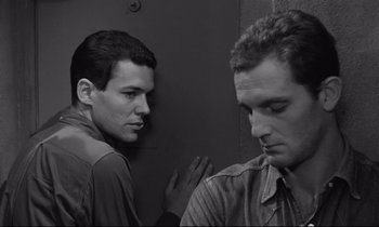 Movie still from “The Hole” (1960), directed by Jacques Becker – Two men standing next to each other in front of a wall; Close Up shot, Over the shoulder angle