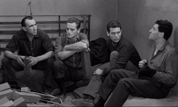 Movie still from “The Hole” (1960), directed by Jacques Becker – A group of men sitting on top of a wooden bench; Medium shot, High angle