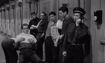 Movie still from “The Hole” (1960), directed by Jacques Becker – A black and white photo of a group of men standing next to each other; Medium shot, High angle