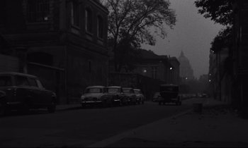 Movie still from “The Hole” (1960), directed by Jacques Becker – An old photo of cars parked on the side of the road; Extreme Wide shot, High angle