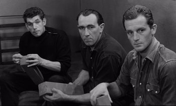 Movie still from “The Hole” (1960), directed by Jacques Becker – A group of men sitting next to each other in a room; Medium shot, High angle