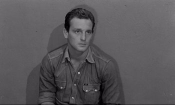 Movie still from “The Hole” (1960), directed by Jacques Becker – A black and white photo of a man wearing a jean shirt; Close Up shot, High angle