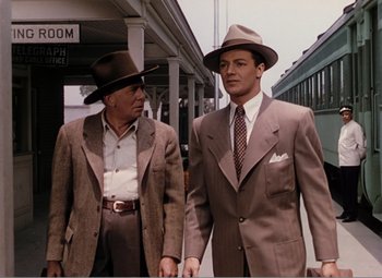 Movie still from “Leave Her to Heaven” (1945), directed by John M. Stahl – Two men in suits and hats walking on the sidewalk; Medium shot, Low angle