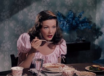 Movie still from “Leave Her to Heaven” (1945), directed by John M. Stahl – A woman sitting at a dinner table with a plate of food; Medium shot, High angle