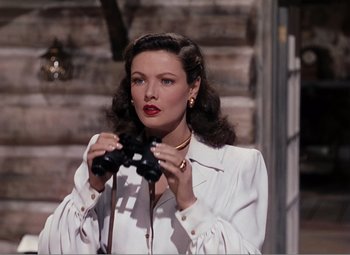 Movie still from “Leave Her to Heaven” (1945), directed by John M. Stahl – A woman holding a pair of binoculars while wearing a white shirt; Medium shot, High angle