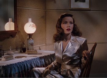Movie still from “Leave Her to Heaven” (1945), directed by John M. Stahl – A woman sitting at a table with a lamp in the background; Medium shot, High angle