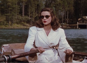 Movie still from “Leave Her to Heaven” (1945), directed by John M. Stahl – A woman in a white suit rowing a boat on a river; Medium shot, High angle