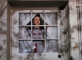 Movie still from “Leave Her to Heaven” (1945), directed by John M. Stahl – A woman standing in a window with curtains open; Medium shot, Low angle