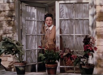 Movie still from “Leave Her to Heaven” (1945), directed by John M. Stahl – A woman standing in front of a window with plants; Medium shot, Low angle