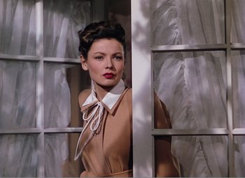 Movie still from “Leave Her to Heaven” (1945), directed by John M. Stahl – A beautiful woman in a brown coat standing in front of a window; Medium shot, Low angle