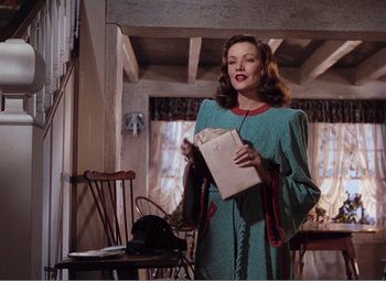 Movie still from “Leave Her to Heaven” (1945), directed by John M. Stahl – A woman in a blue dress holding a paper bag; Medium shot, Low angle