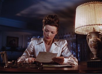 Movie still from “Leave Her to Heaven” (1945), directed by John M. Stahl – A woman sitting at a table writing on a piece of paper; Medium shot, Low angle