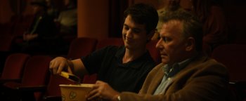 Movie still from “Whiplash” (2014), directed by Damien Chazelle – A man sitting next to another man in a room; Medium shot, Over the shoulder angle