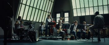Movie still from “Whiplash” (2014), directed by Damien Chazelle – A group of people sitting in a room playing instruments; Extreme Wide shot, Low angle
