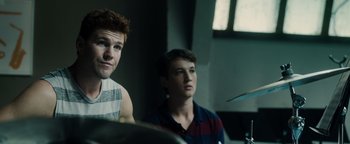 Movie still from “Whiplash” (2014), directed by Damien Chazelle – Two young men sitting next to each other in a room; Close Up shot, Over the shoulder angle