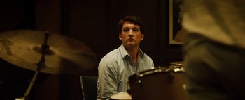 Movie still from “Whiplash” (2014), directed by Damien Chazelle – A man sitting in front of a drum set; Close Up shot, Over the shoulder angle