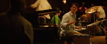 Movie still from “Whiplash” (2014), directed by Damien Chazelle – A man sitting in front of a grand piano in a room; Medium shot, Over the shoulder angle