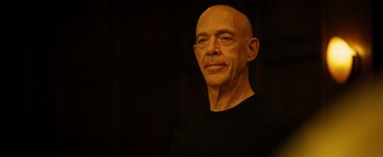 Movie still from “Whiplash” (2014), directed by Damien Chazelle – A bald man wearing a black t - shirt is smiling for the camera; Close Up shot, Low angle