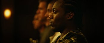 Movie still from “Whiplash” (2014), directed by Damien Chazelle – Three men are standing side by side in the dark; Close Up shot, Over the shoulder angle