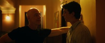 Movie still from “Whiplash” (2014), directed by Damien Chazelle – A man standing next to another man in a room; Medium shot, Low angle