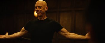Movie still from “Whiplash” (2014), directed by Damien Chazelle – A bald man in a black t - shirt is smiling; Close Up shot, Low angle