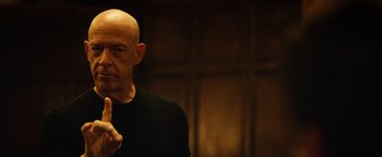 Movie still from “Whiplash” (2014), directed by Damien Chazelle – A bald man in a black shirt is looking at the camera; Close Up shot, Low angle