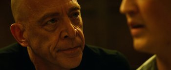 Movie still from “Whiplash” (2014), directed by Damien Chazelle – An older man looking at the camera while sitting down; Close Up shot, Over the shoulder angle