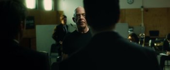 Movie still from “Whiplash” (2014), directed by Damien Chazelle – A man in a black shirt is talking to another man in a black shirt; Medium shot, Over the shoulder angle