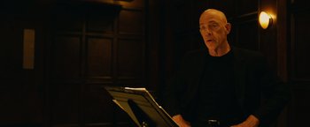 Movie still from “Whiplash” (2014), directed by Damien Chazelle – An older man sitting in front of a sheet of paper; Medium shot, Over the shoulder angle