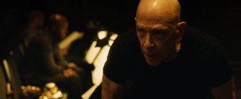 Movie still from “Whiplash” (2014), directed by Damien Chazelle – A bald man in a black t - shirt is looking at the camera; Close Up shot, Low angle