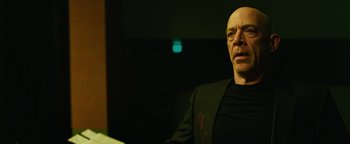 Movie still from “Whiplash” (2014), directed by Damien Chazelle – A bald man in a black shirt and jacket; Close Up shot, Low angle