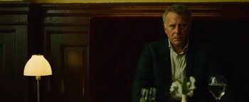 Movie still from “Whiplash” (2014), directed by Damien Chazelle – A man sitting at a table in front of a glass of wine; Close Up shot, Over the shoulder angle