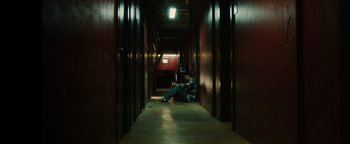 Movie still from “Whiplash” (2014), directed by Damien Chazelle – A man sitting on the ground in a hallway; Wide shot, High angle