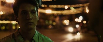 Movie still from “Whiplash” (2014), directed by Damien Chazelle – A man in a green shirt standing on a street; Close Up shot, Over the shoulder angle