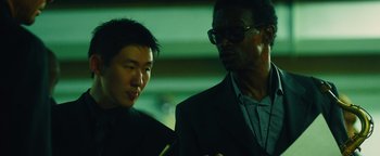 Movie still from “Whiplash” (2014), directed by Damien Chazelle – A man in a suit standing next to another man in a suit; Close Up shot, High angle