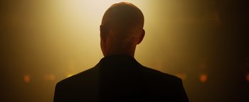 Movie still from “Whiplash” (2014), directed by Damien Chazelle – A man with a bald head is standing in the sunlight; Close Up shot, Low angle