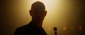 Movie still from “Whiplash” (2014), directed by Damien Chazelle – A man with a bald head is smiling for the camera; Close Up shot, Low angle