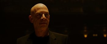 Movie still from “Whiplash” (2014), directed by Damien Chazelle – A bald man in a black jacket and a black shirt; Close Up shot, Low angle
