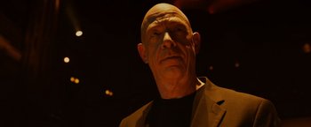 Movie still from “Whiplash” (2014), directed by Damien Chazelle – A man with bald head wearing a black shirt and jacket; Close Up shot, Low angle