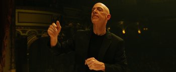 Movie still from “Whiplash” (2014), directed by Damien Chazelle – A bald man in a black jacket is holding his hands up; Close Up shot, Low angle