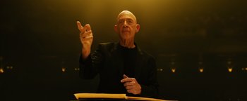 Movie still from “Whiplash” (2014), directed by Damien Chazelle – A man in a black jacket is holding his hands up; Medium shot, Low angle