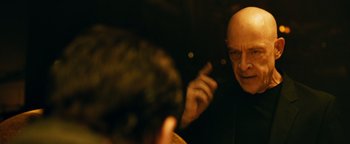 Movie still from “Whiplash” (2014), directed by Damien Chazelle – A man with bald head talking to another man in a dark room; Close Up shot, Over the shoulder angle