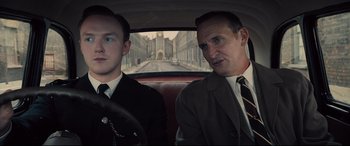 Movie still from “Legend” (2015), directed by Brian Helgeland – Two men sitting in the back seat of a car; Medium shot, Over the shoulder angle