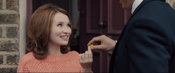 Movie still from “Legend” (2015), directed by Brian Helgeland – A woman holding a yellow object in front of a man; Close Up shot, Over the shoulder angle