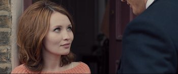Movie still from “Legend” (2015), directed by Brian Helgeland – A woman in a pink sweater looking up at a man; Close Up shot, Over the shoulder angle