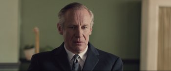 Movie still from “Legend” (2015), directed by Brian Helgeland – An older man wearing a suit and tie; Close Up shot, Over the shoulder angle