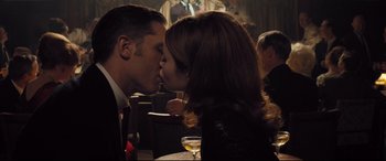 Movie still from “Legend” (2015), directed by Brian Helgeland – A man and a woman kissing in a restaurant; Medium shot, Low angle